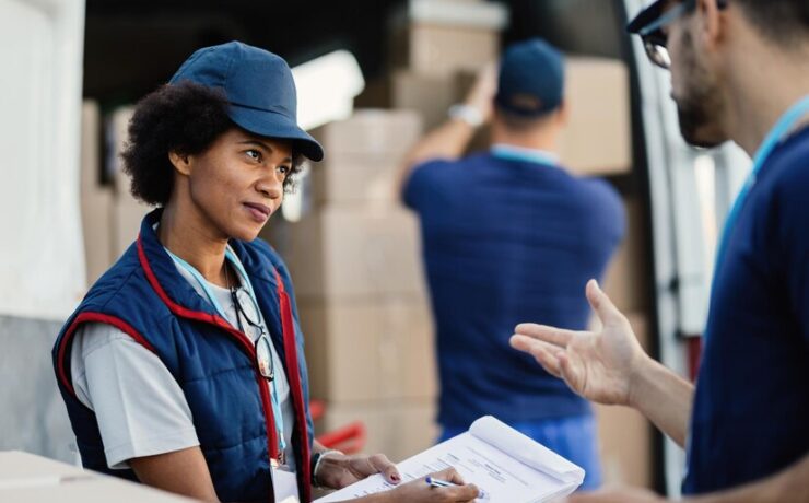 two-deliverers-communicating-going-through-paperwork-while-their-colleagues-is-loading-packages-van-focus-is-african-american-woman_637285-1256
